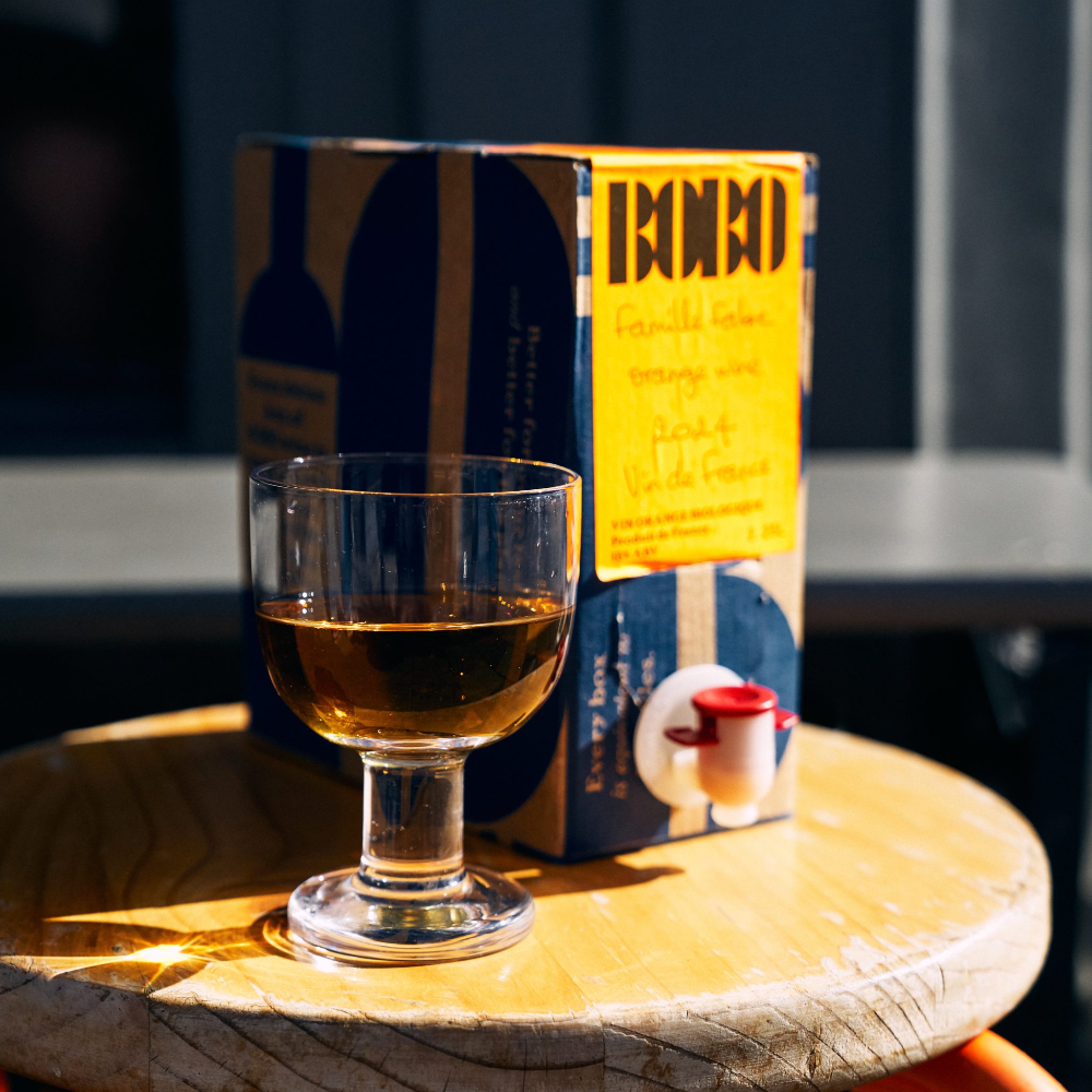 Wine glass with a box of organic skin contact wine on a wooden table