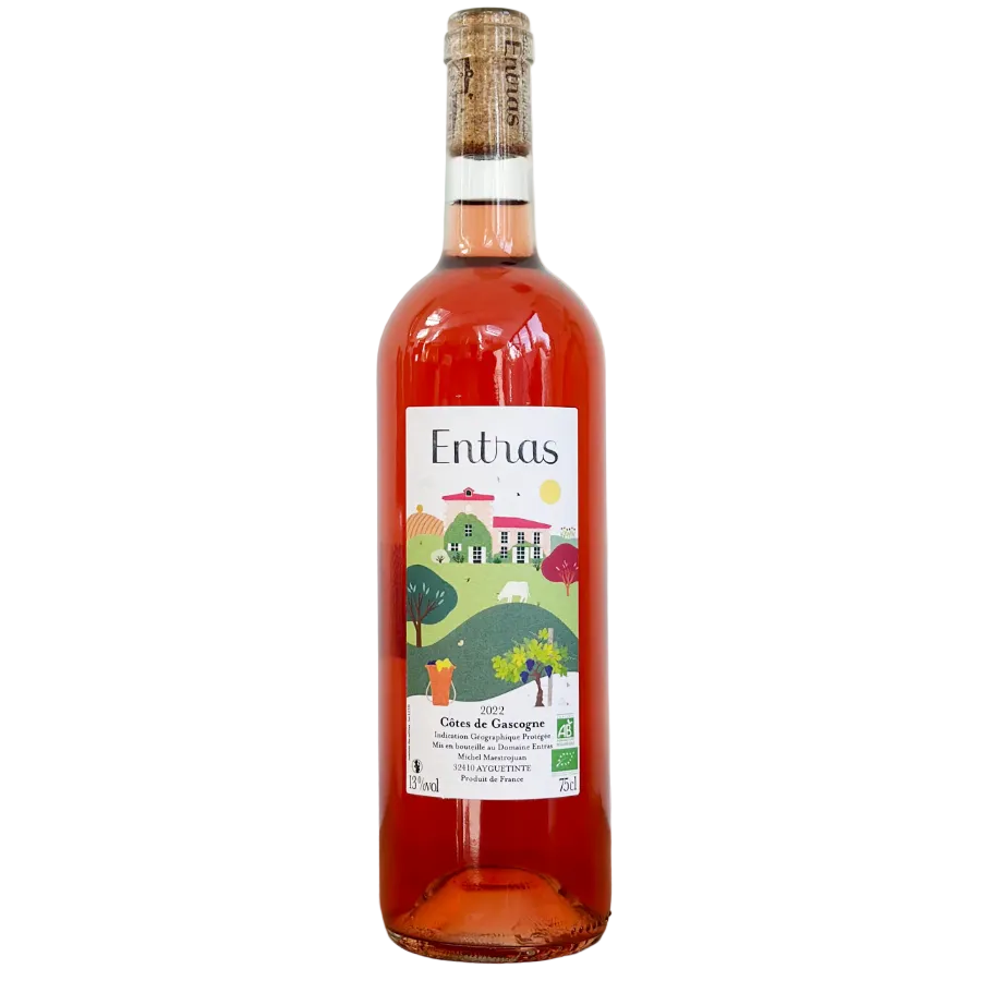 A bottle of Entras Côtes de Gascogne rosé wine with a cork stopper, featuring a colorful landscape label, set on a wooden surface against a plain white background.
