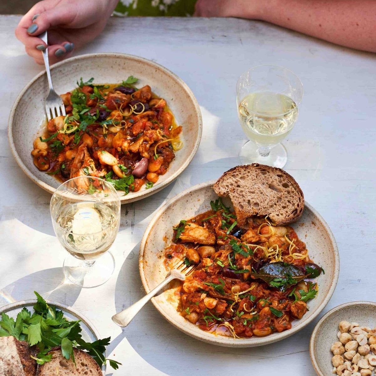 Two plates of Fieldgoods Spanish with bread and wine glasses on a table