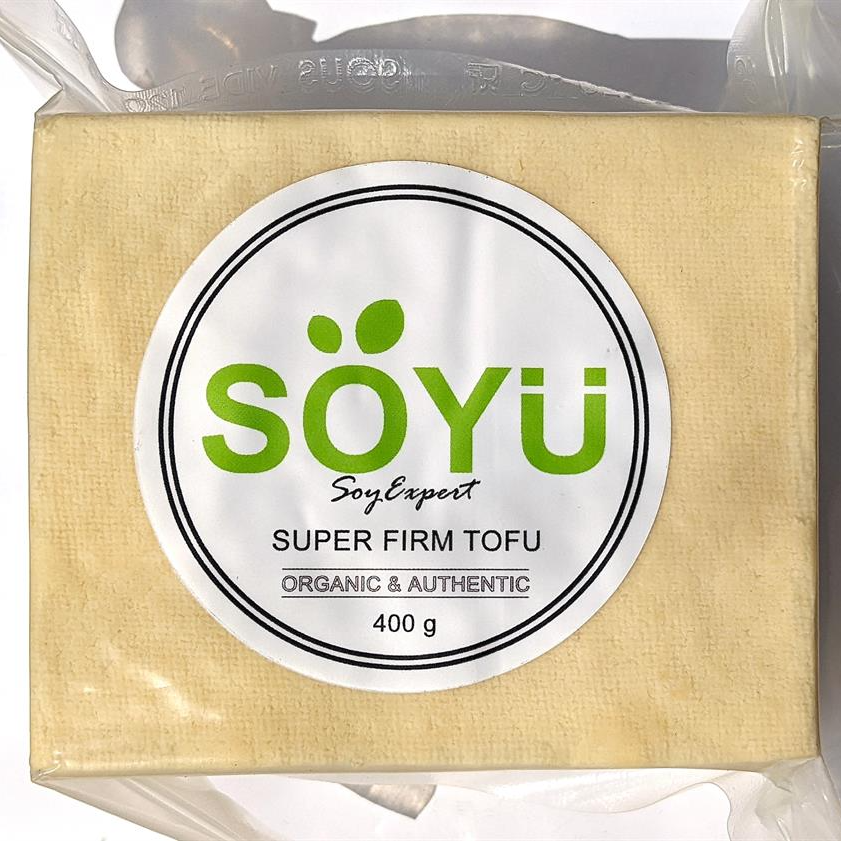 Block of SOYU super firm organic tofu packaging with a clear plastic wrap on a white background