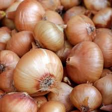 A close-up pile of fresh yellow onions with their papery golden-brown outer skins visible.